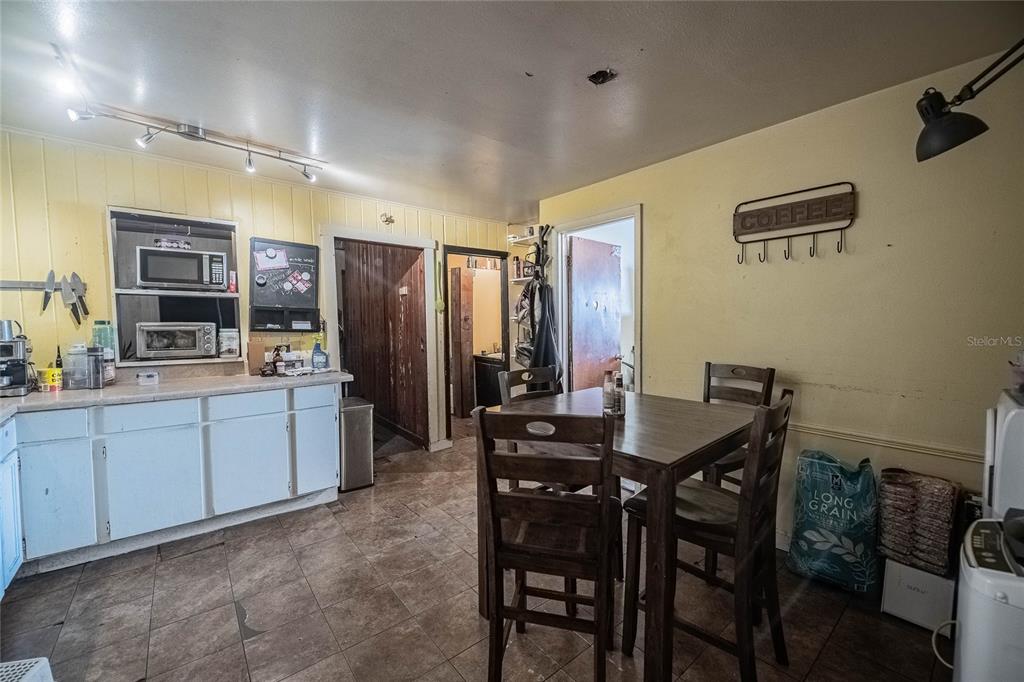 A kitchen with white cabinets, a dining table, and yellow walls with wood paneling — 2236 BURNS STREET, LAKELAND, FL