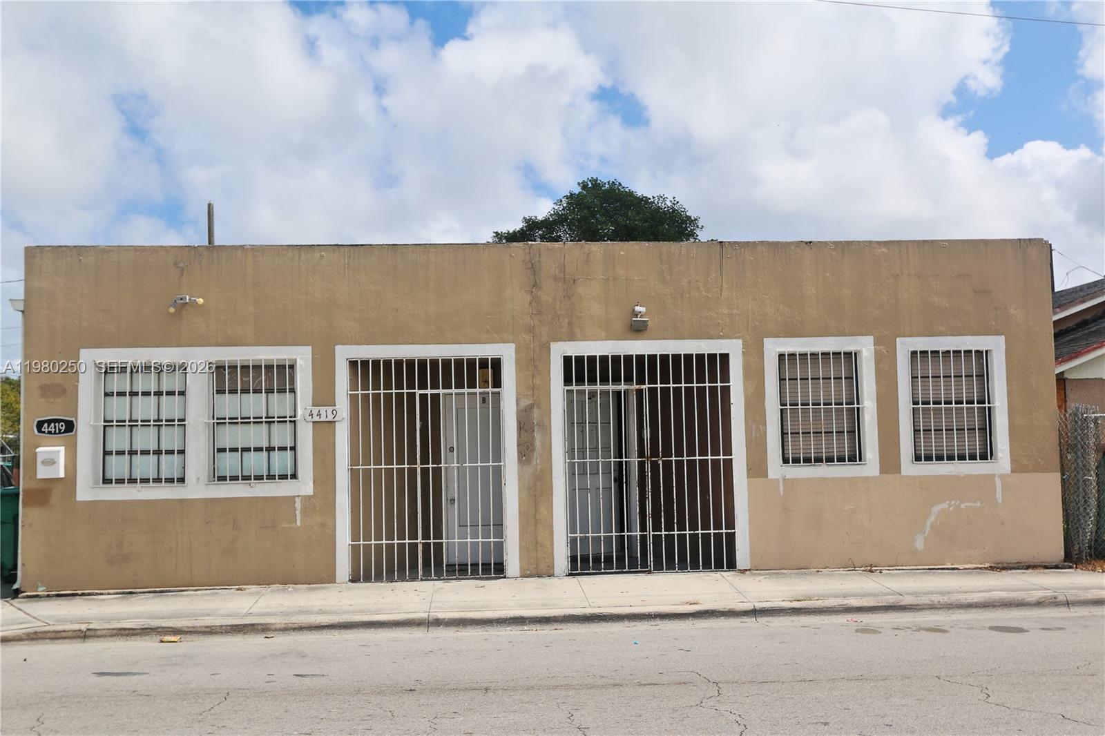 A single-story tan building features two barred entryways and two sets of barred windows — 4419 NW 17th Ave, Miami FL 33142, MIAMI, FL