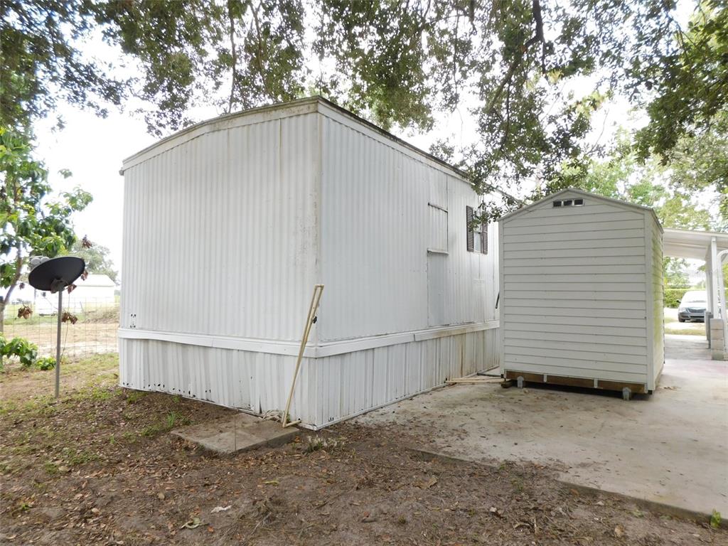 A white mobile home stands next to a small storage shed on a concrete pad — 1110 NE FORREST AVENUE, ARCADIA, FL