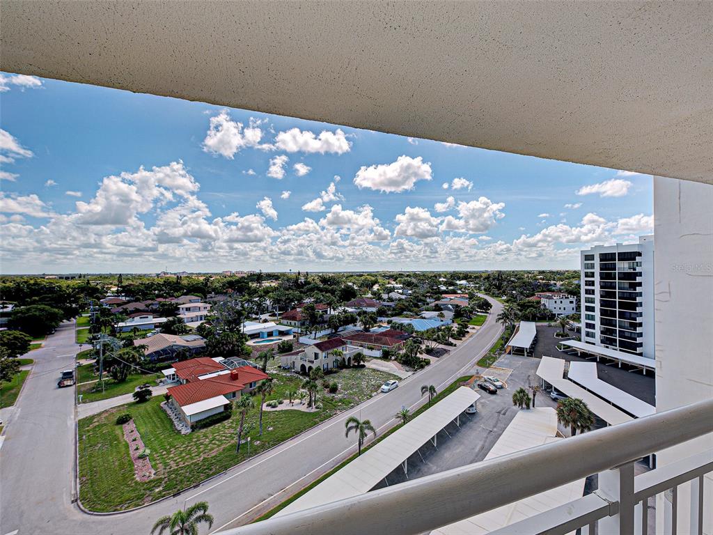 A high-angle view from a balcony overlooks a suburban neighborhood, a road, and parking structures — 633 ALHAMBRA ROAD UNIT 1006, VENICE, FL