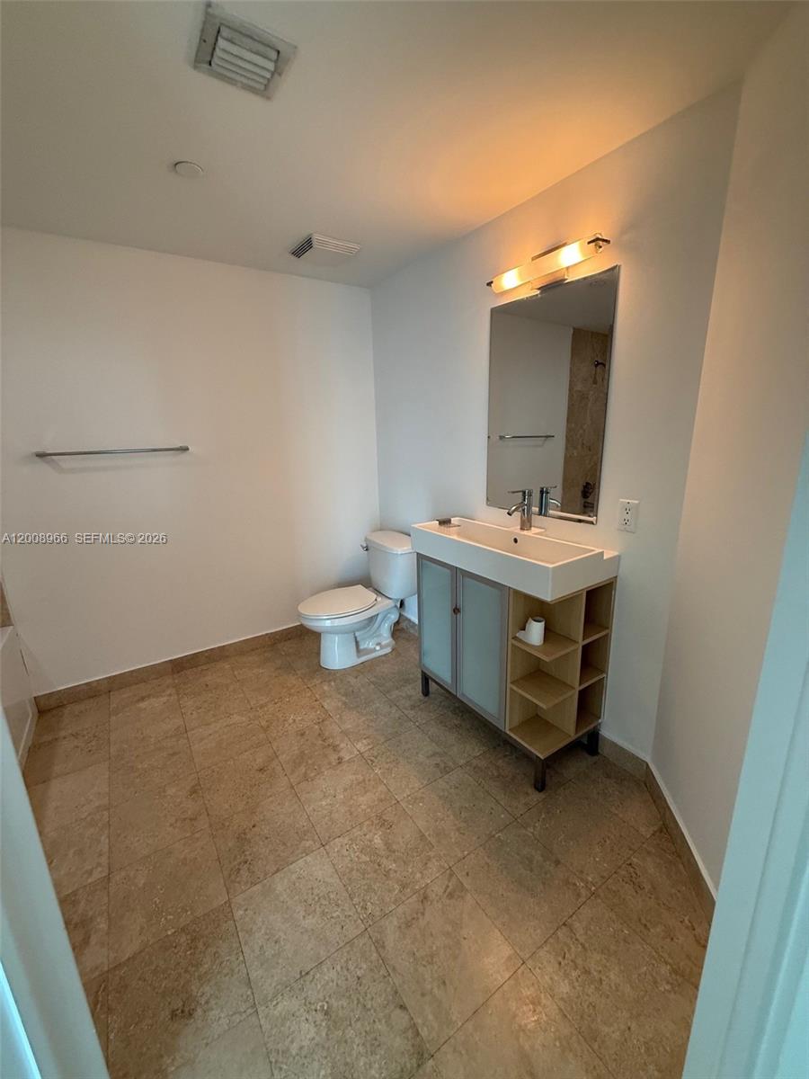 A bathroom features a floating vanity with open shelving, a toilet, and beige tile flooring — 350 S Miami Ave # 2603, Miami FL 33130, MIAMI, FL