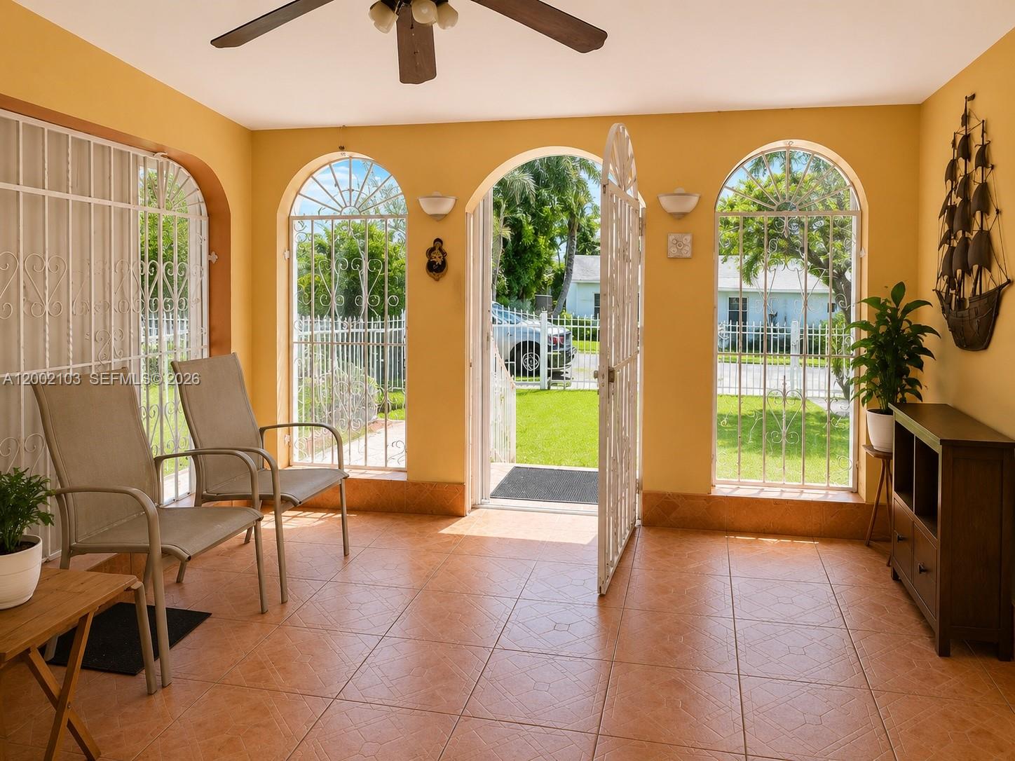 A sunroom features tiled floors, arched windows with security grilles, and an open exterior door — 10820 NE 5th Ave, Miami FL 33161, MIAMI, FL
