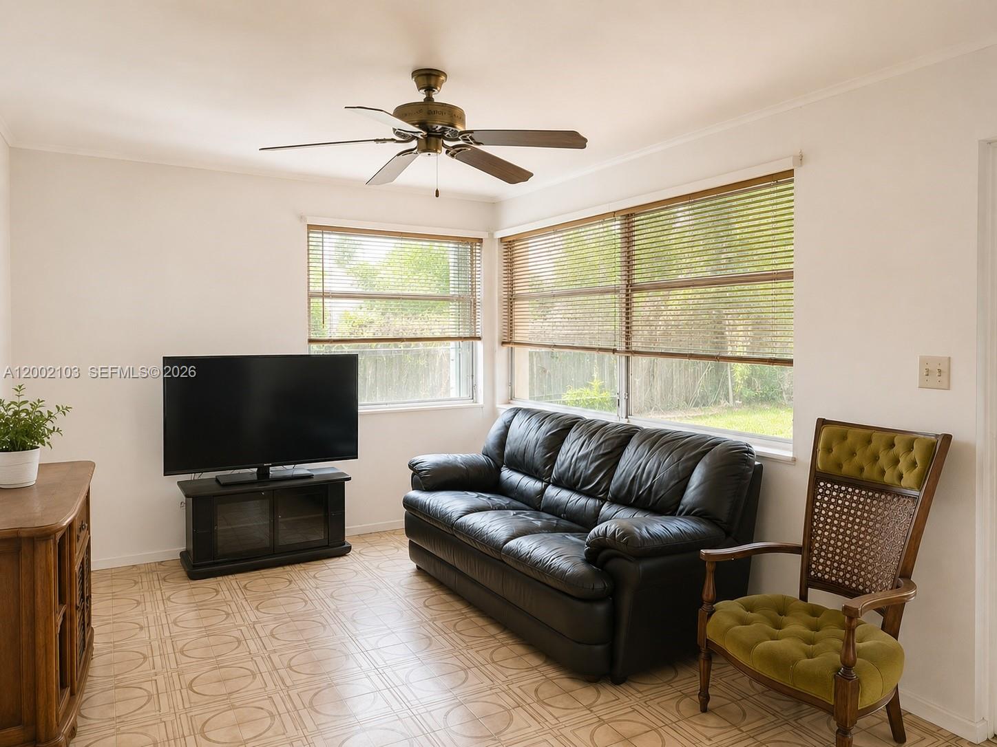 A living room features a black leather sofa, a television, and a vintage green chair — 10820 NE 5th Ave, Miami FL 33161, MIAMI, FL