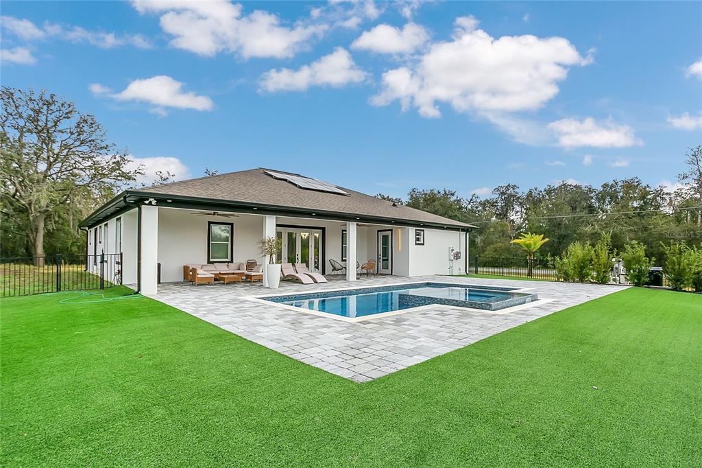 A modern house exterior features a covered patio, swimming pool, and artificial turf lawn — 18965 SHELDON STREET, ORLANDO, FL
