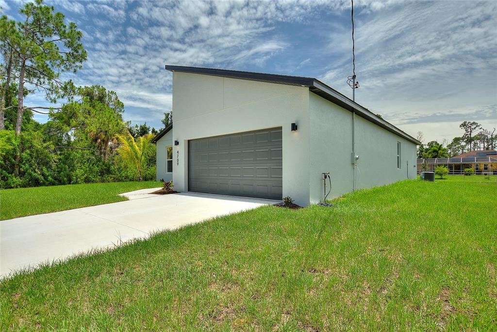 A single-story house with a gray garage door and a slanted roof sits on grass — 4709 FLINT DRIVE, NORTH PORT, FL