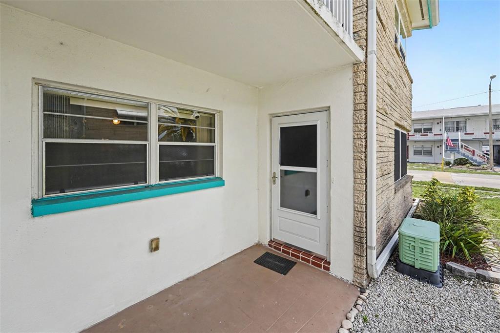 A ground-level exterior entryway features a white door, a window, and a concrete porch — 5855 18TH STREET N UNIT 1, ST PETERSBURG, FL