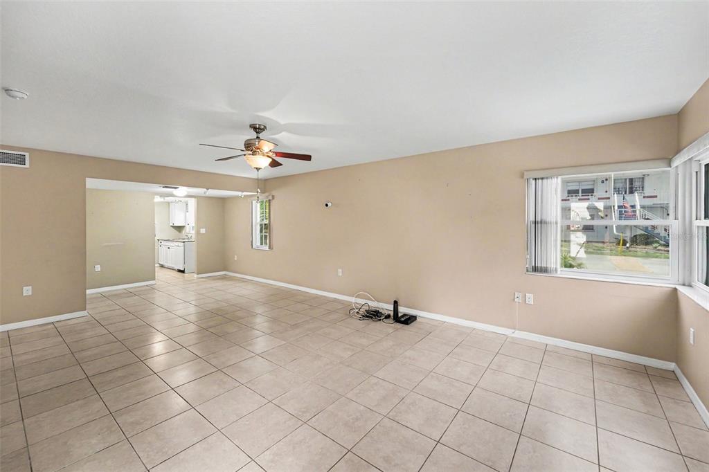 An empty living room with beige tile flooring, tan walls, and a ceiling fan — 5855 18TH STREET N UNIT 1, ST PETERSBURG, FL