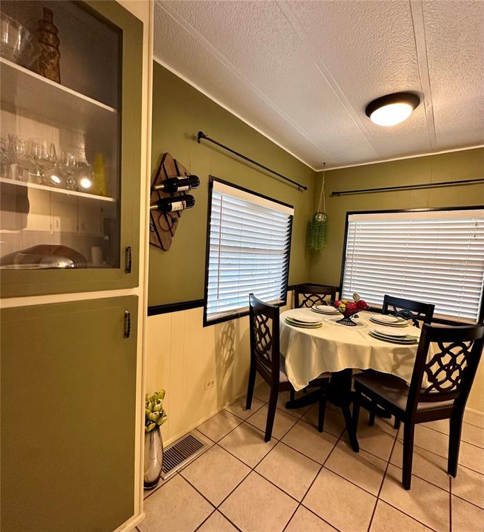 A dining area features a round table, chairs, olive green walls, and a built-in cabinet — 1100 BELCHER ROAD S UNIT 185, LARGO, FL