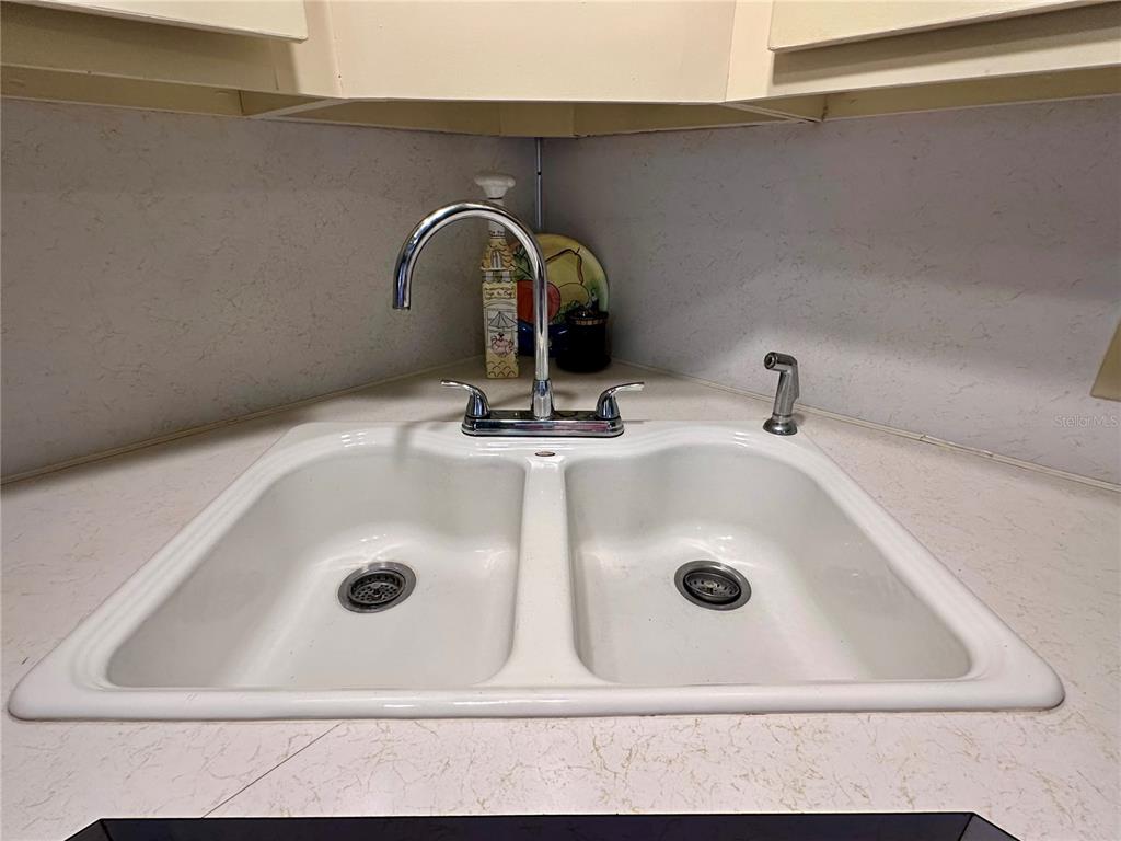 A white double-basin kitchen sink with a chrome faucet is set in a corner countertop — 1100 BELCHER ROAD S UNIT 185, LARGO, FL