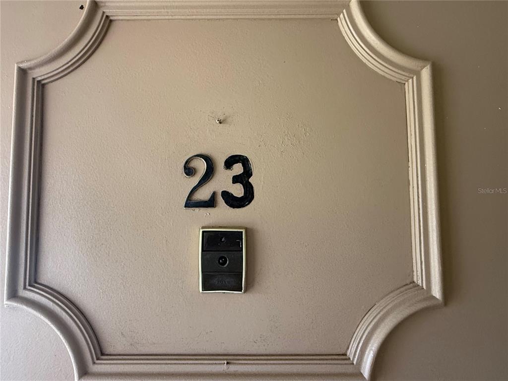 A beige door features the number 23 and a doorbell button — 10038 62ND TERRACE N UNIT 23, SEMINOLE, FL