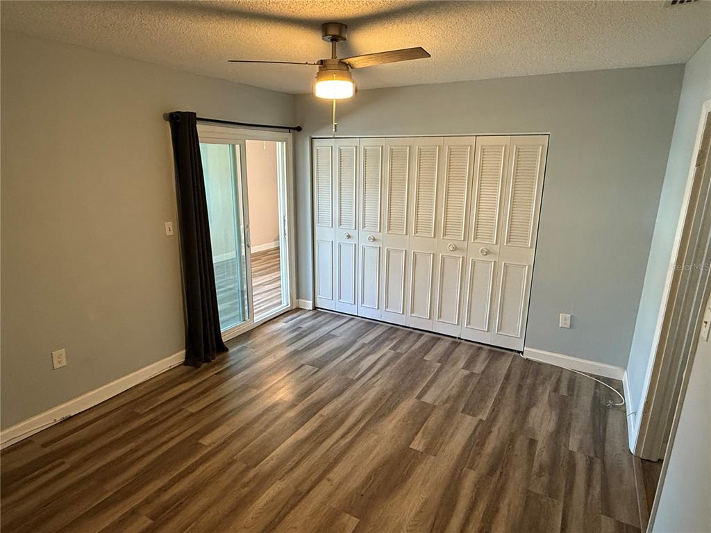 A bedroom features light gray walls, wood-look flooring, a ceiling fan, and white louvered closet doors — 10038 62ND TERRACE N UNIT 23, SEMINOLE, FL