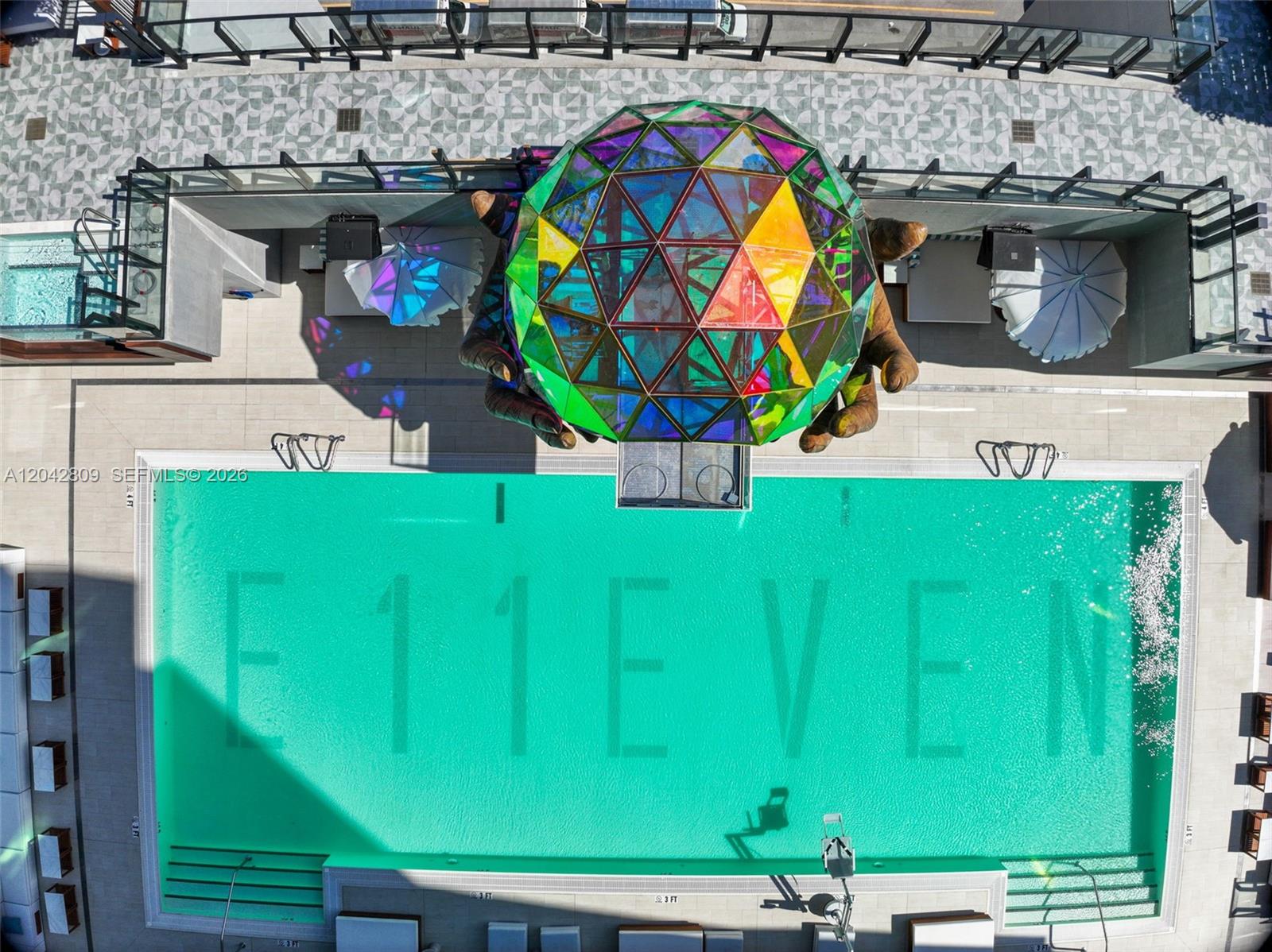 An aerial view shows a swimming pool with the word E11EVEN and a geometric sculpture — 20 NE 11 # 2410, Miami FL 33132, MIAMI, FL