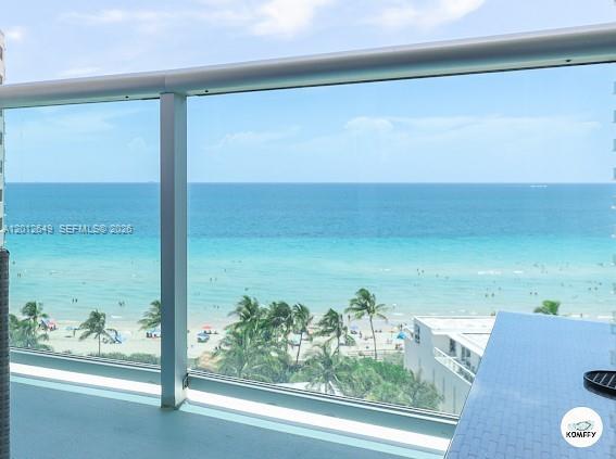 A view of the ocean and beach from a balcony with a glass railing — 3901 S Ocean Dr # 11M, Hollywood FL 33019, HOLLYWOOD, FL