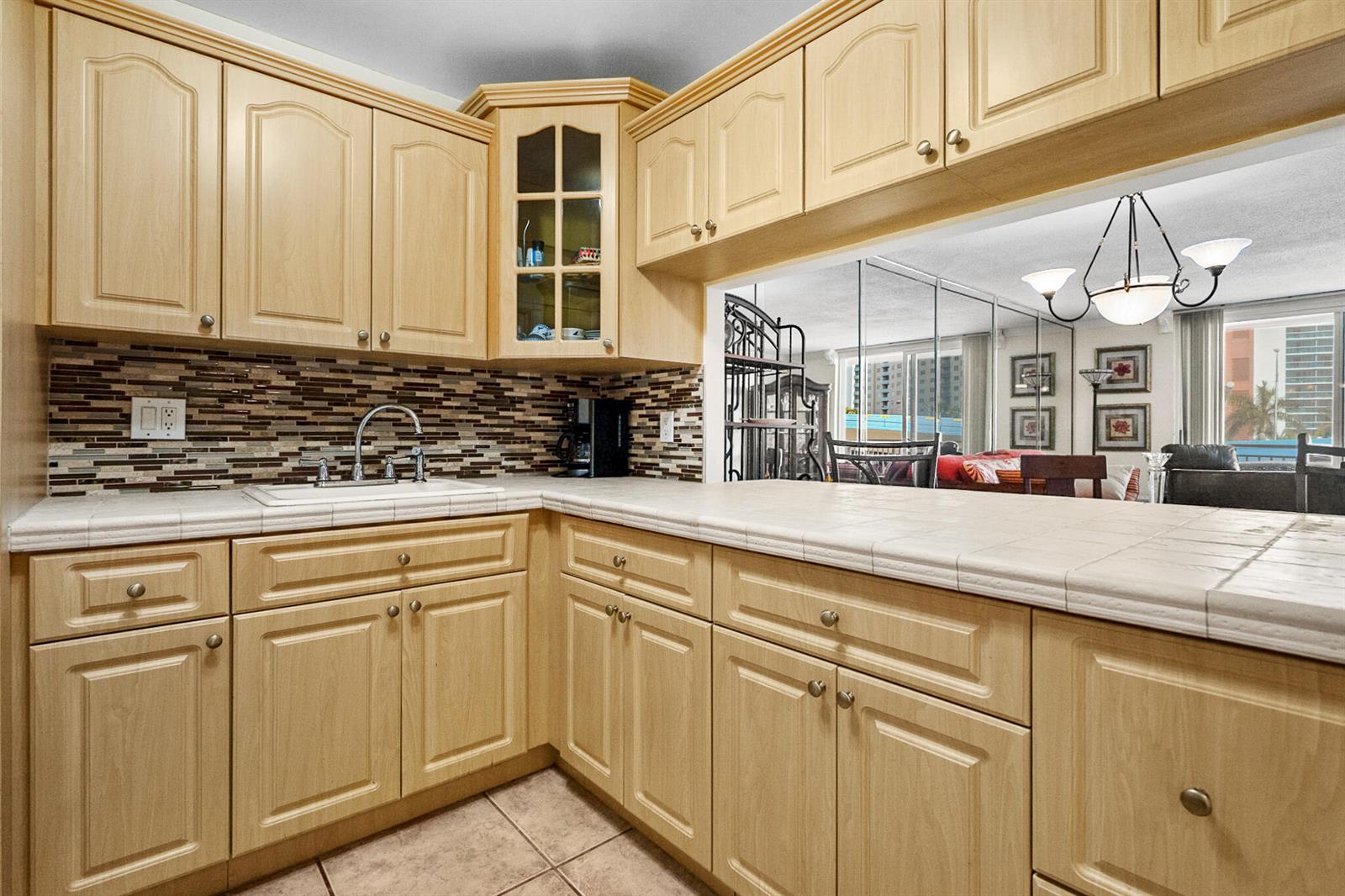 A kitchen features light wood cabinets, a tiled countertop, and a mosaic tile backsplash — 1801 S Ocean Drive Unit 332, Hallandale Beach FL 33009, HALLANDALE BEACH, FL
