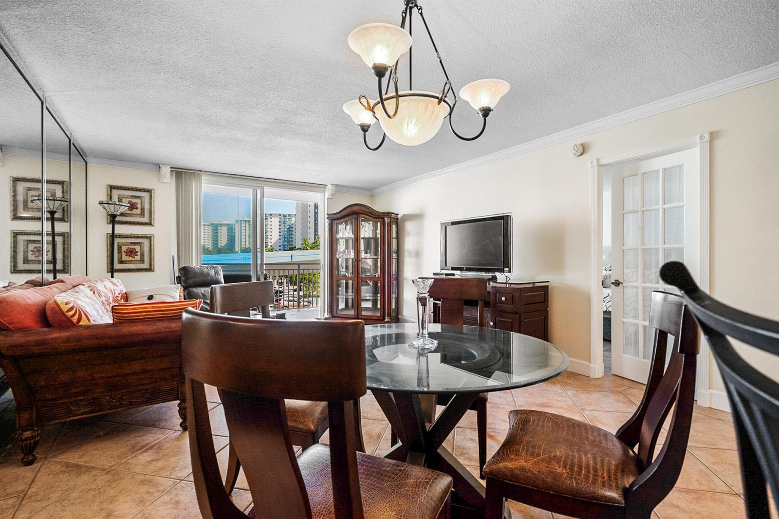 A dining area with a glass table and chairs sits before a living room balcony — 1801 S Ocean Drive Unit 332, Hallandale Beach FL 33009, HALLANDALE BEACH, FL