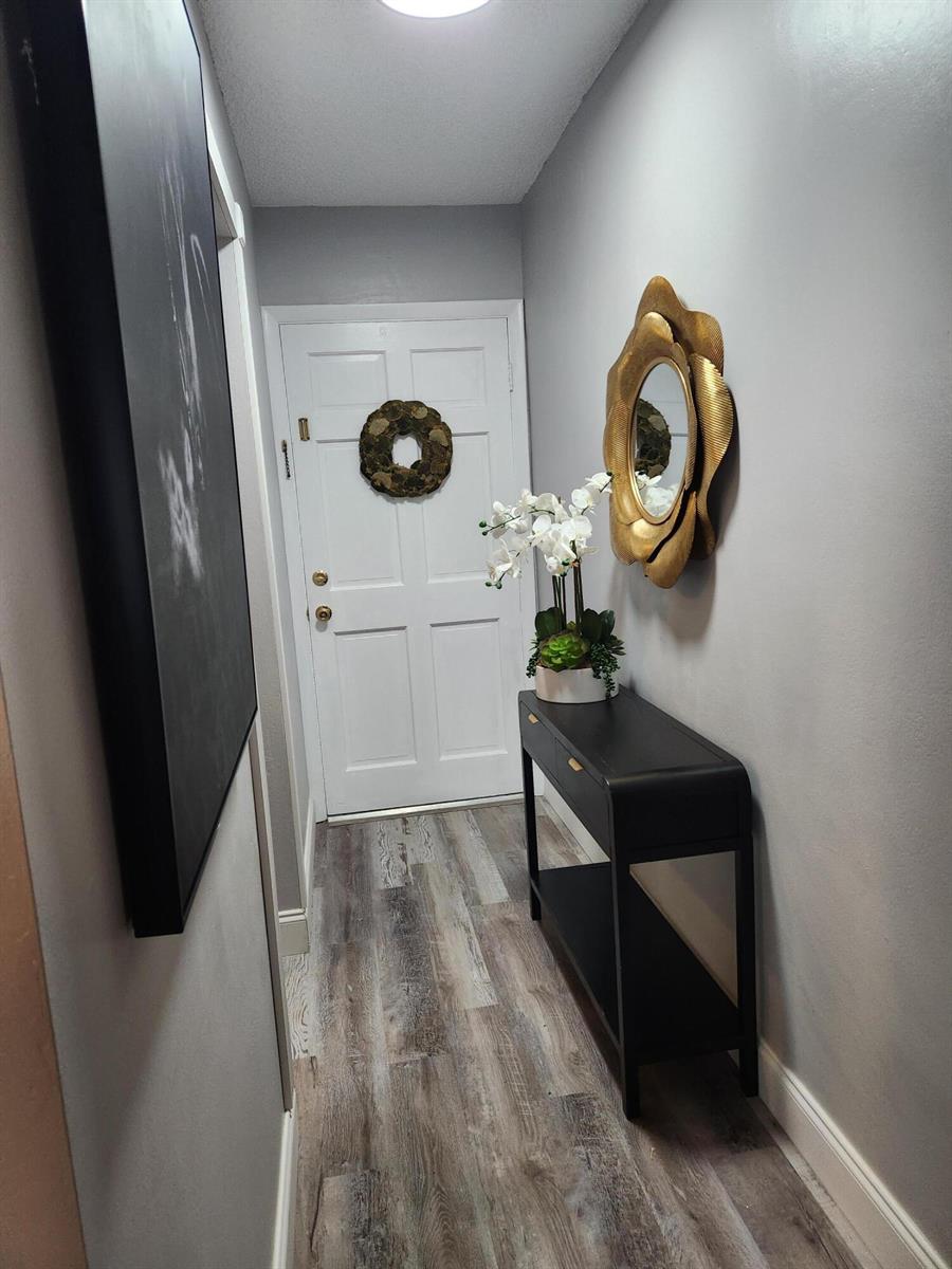 A narrow entryway features a black console table, a gold mirror, and wood-look flooring — 2606 Garden Drive # 304, FL 33461, FL