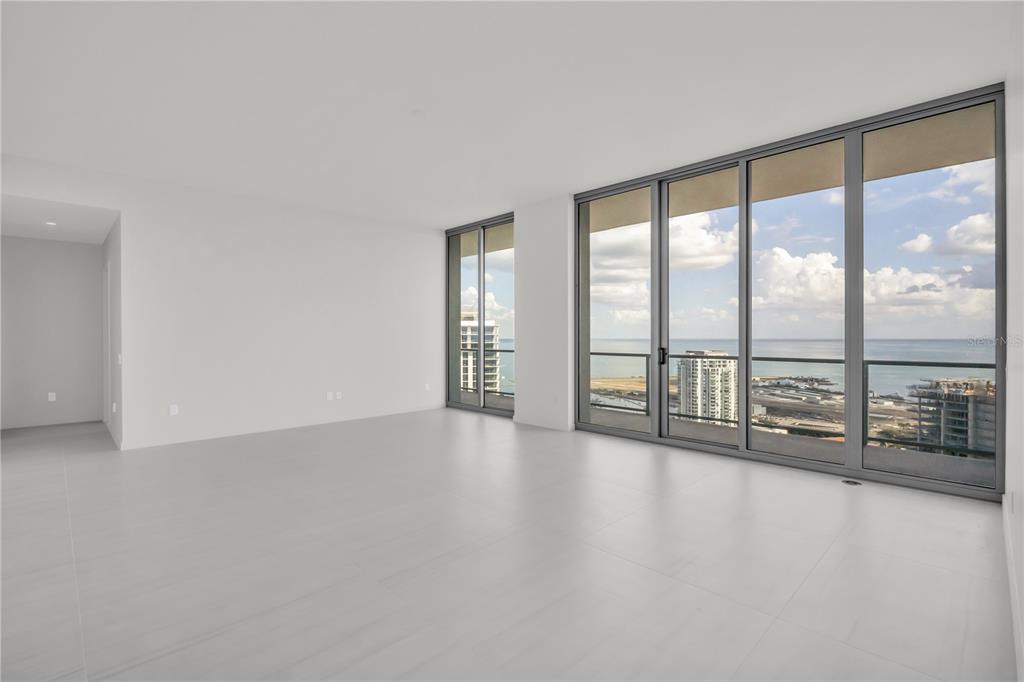 An empty room with white walls, light tile flooring, and floor-to-ceiling windows overlooking the ocean — 400 CENTRAL AVENUE UNIT 4002, ST PETERSBURG, FL