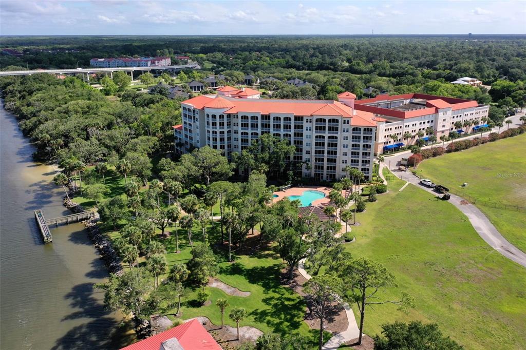 An aerial view shows a large multi-story hotel building with a pool and waterfront dock — 146 PALM COAST RESORT BOULEVARD UNIT 203, PALM COAST, FL