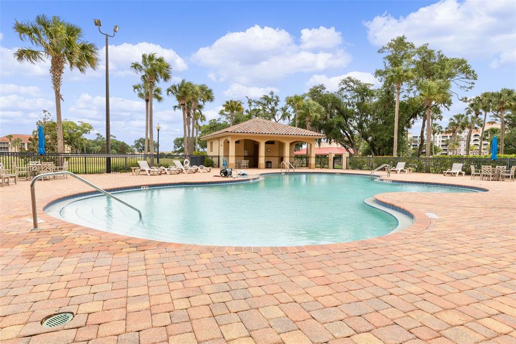A swimming pool with a surrounding brick patio and a covered pavilion in the background — 146 PALM COAST RESORT BOULEVARD UNIT 203, PALM COAST, FL