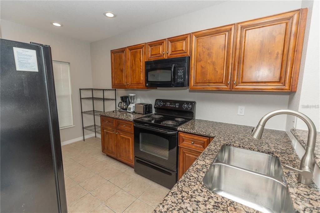 A kitchen features wood cabinets, granite countertops, black appliances, and a stainless steel double sink — 8403 PLACIDA ROAD UNIT 303, PLACIDA, FL
