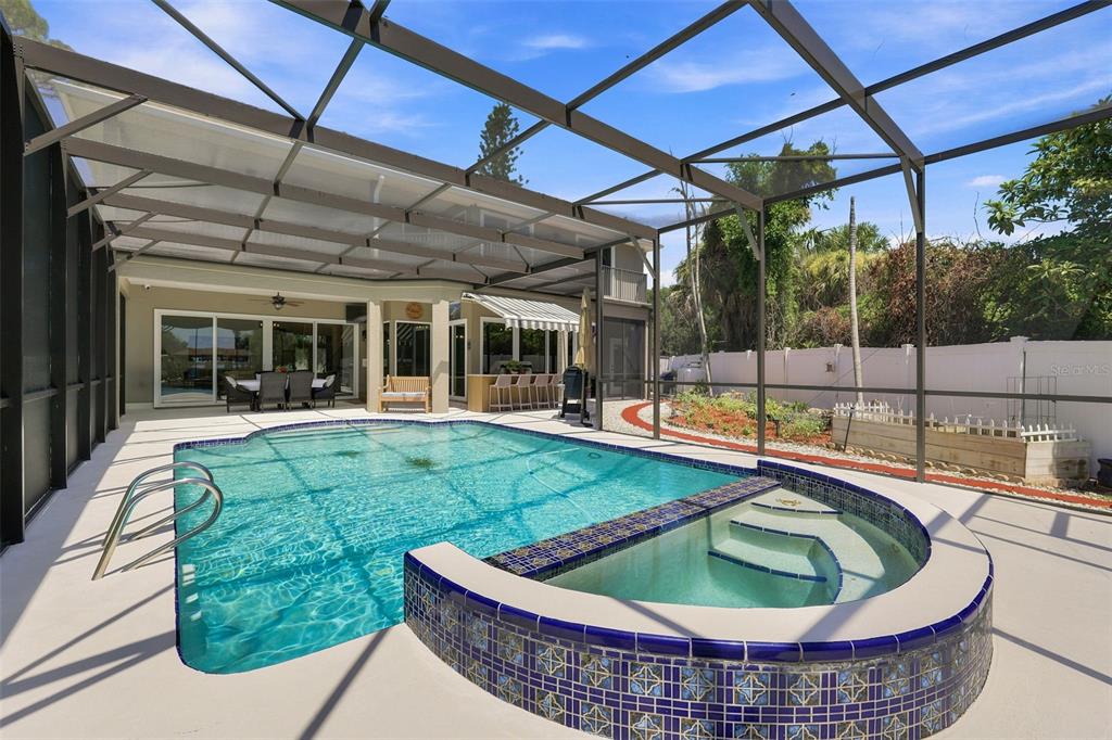 A screened-in patio features a swimming pool, a raised spa, and an outdoor bar area — 2340 NEWFOUND HARBOR DRIVE, MERRITT ISLAND, FL
