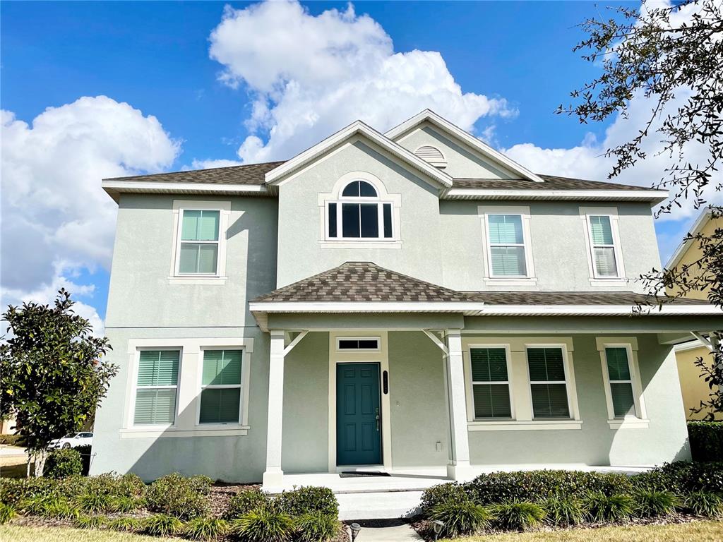 A two-story light green house with a covered front porch and a dark blue door — 7952 HAMPTON LAKE DRIVE, TAMPA, FL