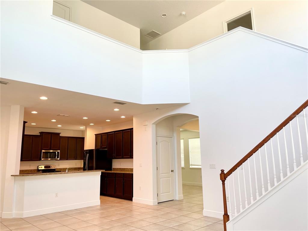 A two-story interior view shows a kitchen with dark cabinets and a staircase with railings — 7952 HAMPTON LAKE DRIVE, TAMPA, FL