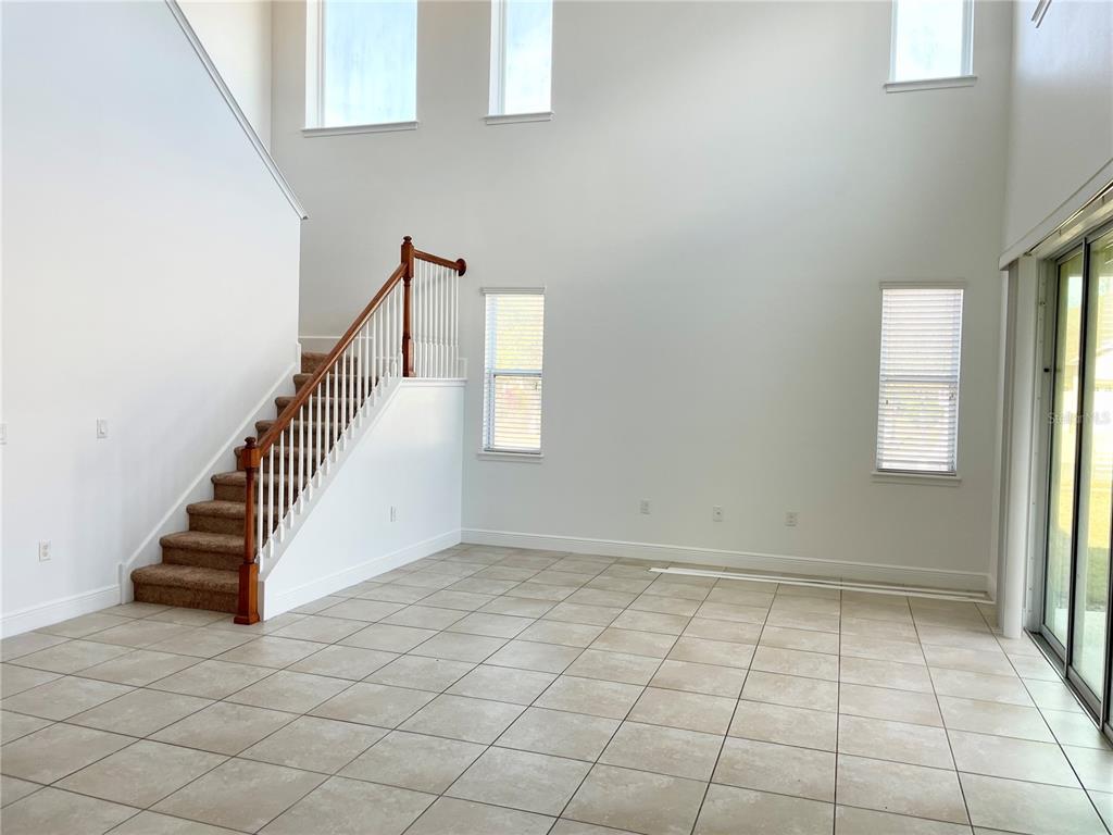 A bright living area features tile flooring, a carpeted staircase, and high ceilings with windows — 7952 HAMPTON LAKE DRIVE, TAMPA, FL