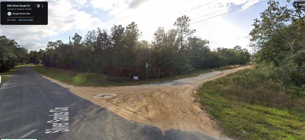 A dirt road intersection is surrounded by dense trees and vegetation under a bright sky — 5795 BLUE RIDGE COURT, KEYSTONE HEIGHTS, FL