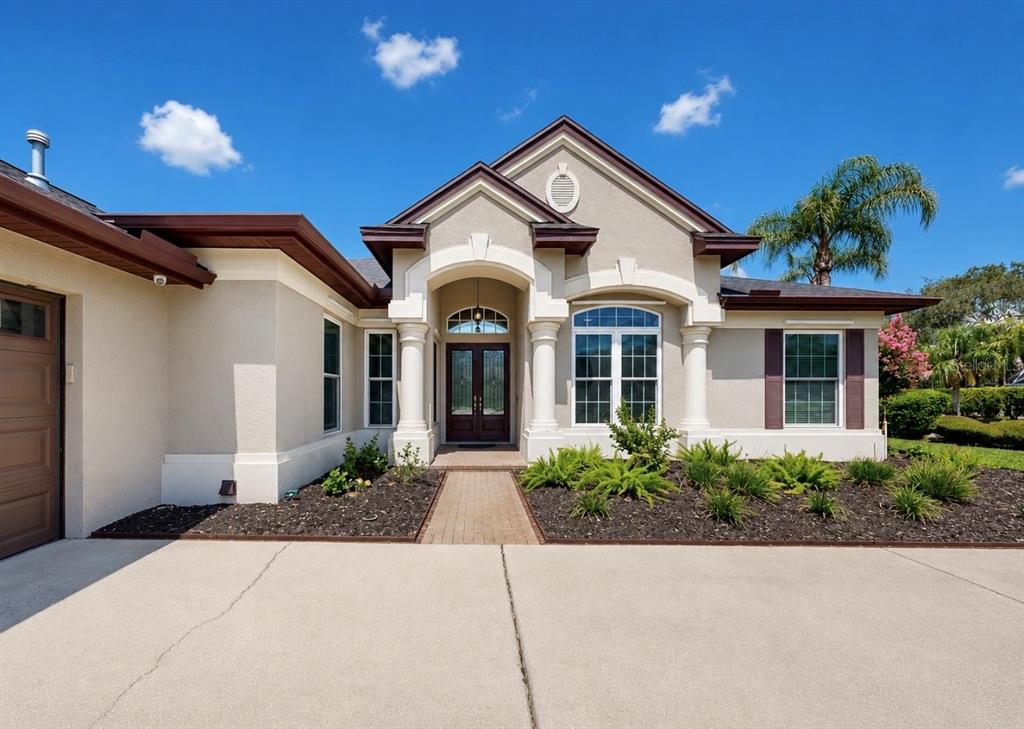 A single-story house with a beige stucco exterior, a brick walkway, and a double-door entrance — 6105 AUDUBON MANOR BOULEVARD, LITHIA, FL