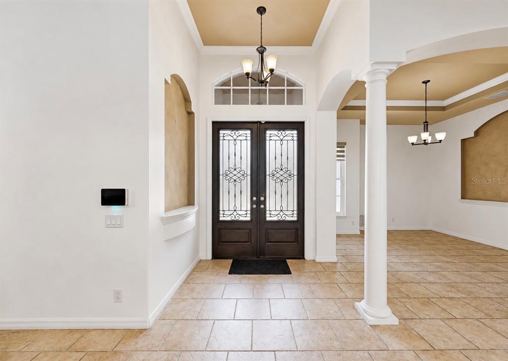A tiled entryway features double front doors, a chandelier, and a white support column — 6105 AUDUBON MANOR BOULEVARD, LITHIA, FL