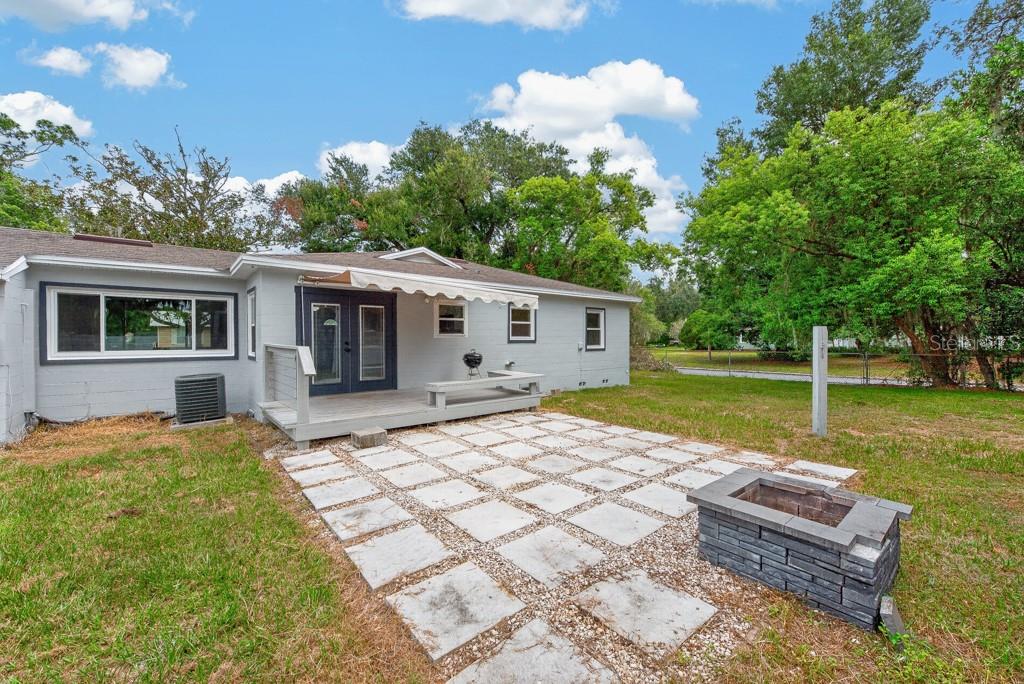 A gray house exterior features a wooden deck, a stone patio, and a fire pit — 215 S ELM ROAD, LAKELAND, FL