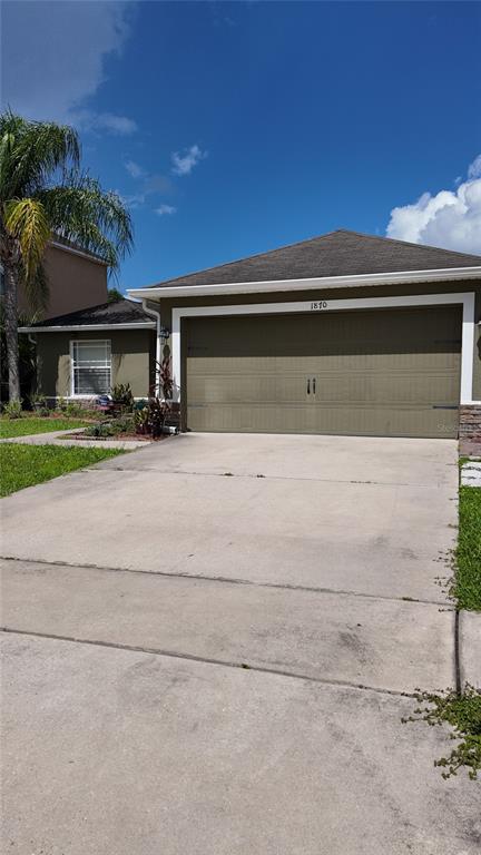 A single-story house with a tan garage and a concrete driveway under a blue sky — 1870 RUFUS KING DRIVE, ST CLOUD, FL