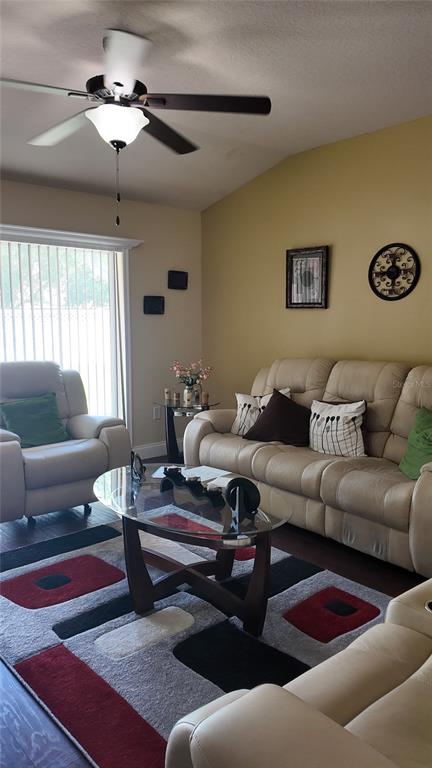 A living room features a beige sofa, a matching armchair, and a glass-topped coffee table — 1870 RUFUS KING DRIVE, ST CLOUD, FL
