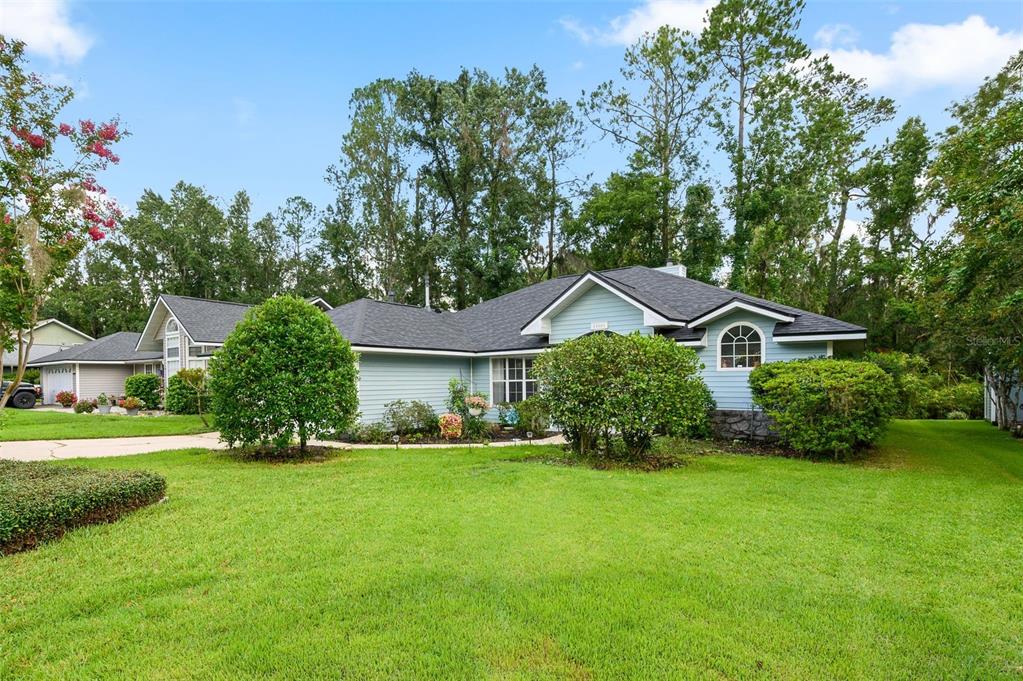 A light blue single-story house with a dark shingled roof and a green lawn — 10001 NW 12TH LANE, GAINESVILLE, FL