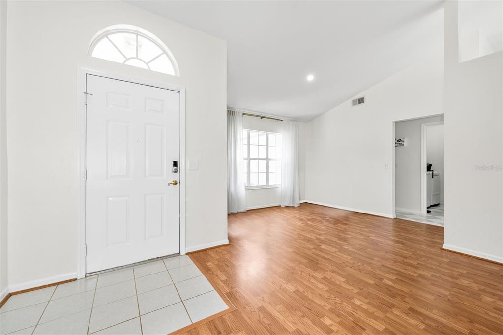 An entryway with tile flooring leads into a living room featuring wood-look floors and windows — 10001 NW 12TH LANE, GAINESVILLE, FL