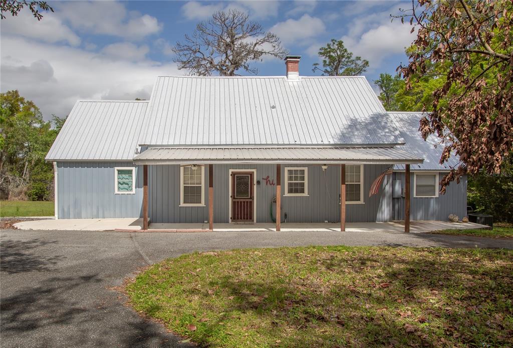 A one-story house with blue vertical siding, a metal roof, and a covered front porch — 1905 MYRTLE LAKE AVENUE, FRUITLAND PARK, FL