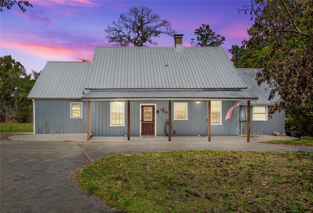 A single-story house with a metal roof and a covered front porch at dusk — 1905 MYRTLE LAKE AVENUE, FRUITLAND PARK, FL
