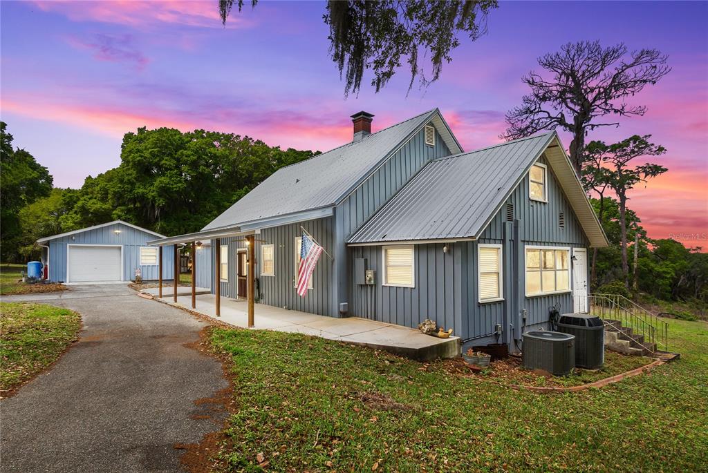 A blue house with a metal roof and a detached garage sits on a grassy lot — 1905 MYRTLE LAKE AVENUE, FRUITLAND PARK, FL