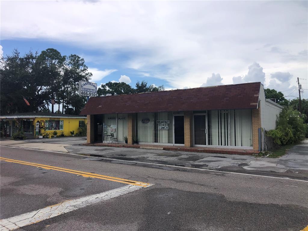 A single-story commercial building with a brown shingled roof sits beside a yellow structure — 1726 N FORT HARRISON AVENUE, CLEARWATER, FL