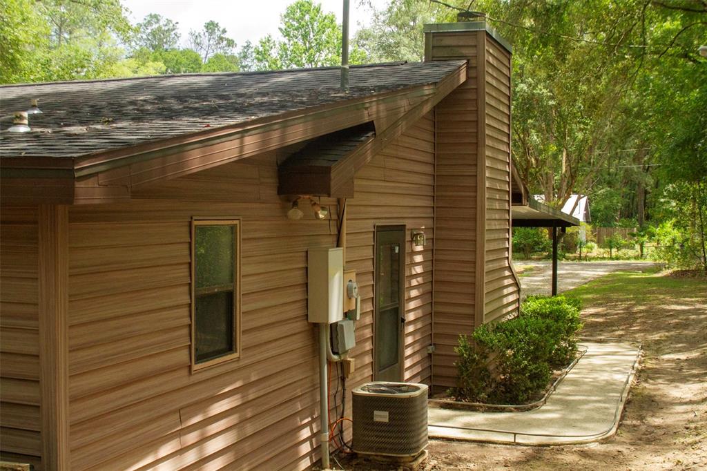 The exterior of a brown-sided house features a chimney, an air conditioning unit, and walkway — 16326 NW 118TH PLACE, ALACHUA, FL