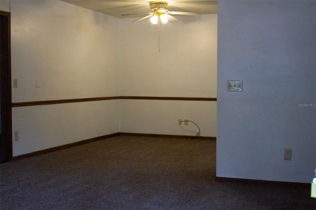 An empty room features beige carpet, white walls with chair rail molding, and a ceiling fan — 16326 NW 118TH PLACE, ALACHUA, FL