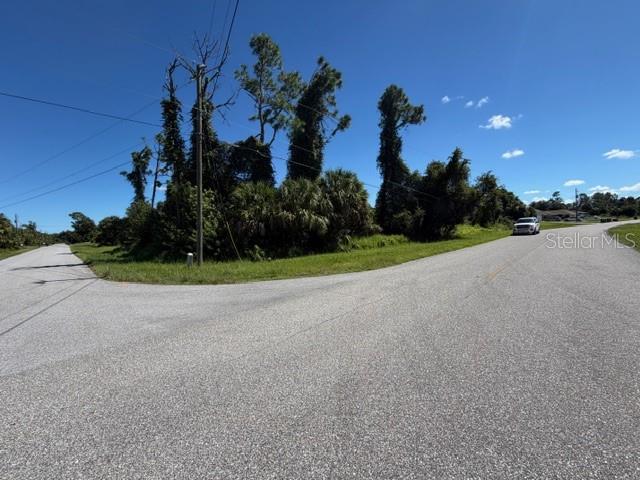 A paved road intersection borders a wooded lot with tall trees and dense vegetation — Lot 1 NORDENDALE BOULEVARD, NORTH PORT, FL