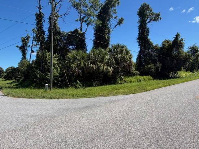 A paved road curves past a vacant, wooded lot with tall trees and dense vegetation — Lot 1 NORDENDALE BOULEVARD, NORTH PORT, FL
