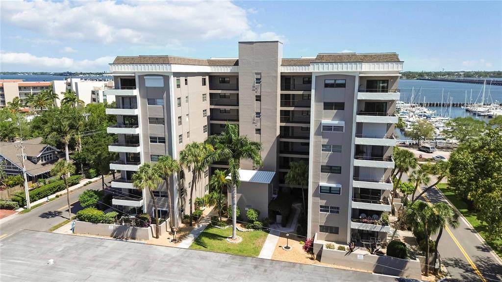 An aerial view of a multi-story apartment building with balconies near a marina — 1400 BARCARROTA BOULEVARD UNIT 201, BRADENTON, FL