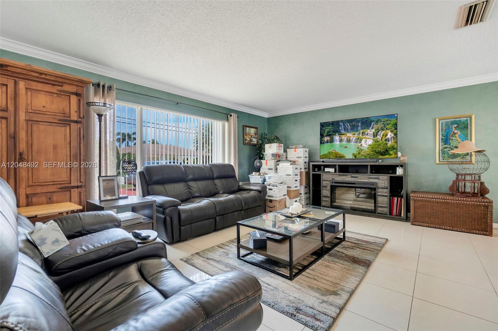 A living room features dark leather sofas, a glass coffee table, and a television console — 2480 NE 46th St, Lighthouse Point FL 33064, LIGHTHOUSE POINT, FL