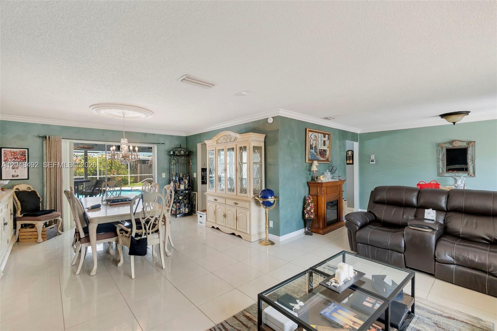 A dining area and living room feature light tile floors, green walls, and a fireplace — 2480 NE 46th St, Lighthouse Point FL 33064, LIGHTHOUSE POINT, FL