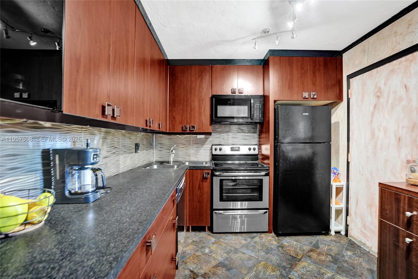 A kitchen features dark wood cabinets, black appliances, a stainless steel stove, and tiled flooring — 1000 NE 12th Ave # 505, Hallandale Beach FL 33009, HALLANDALE BEACH, FL