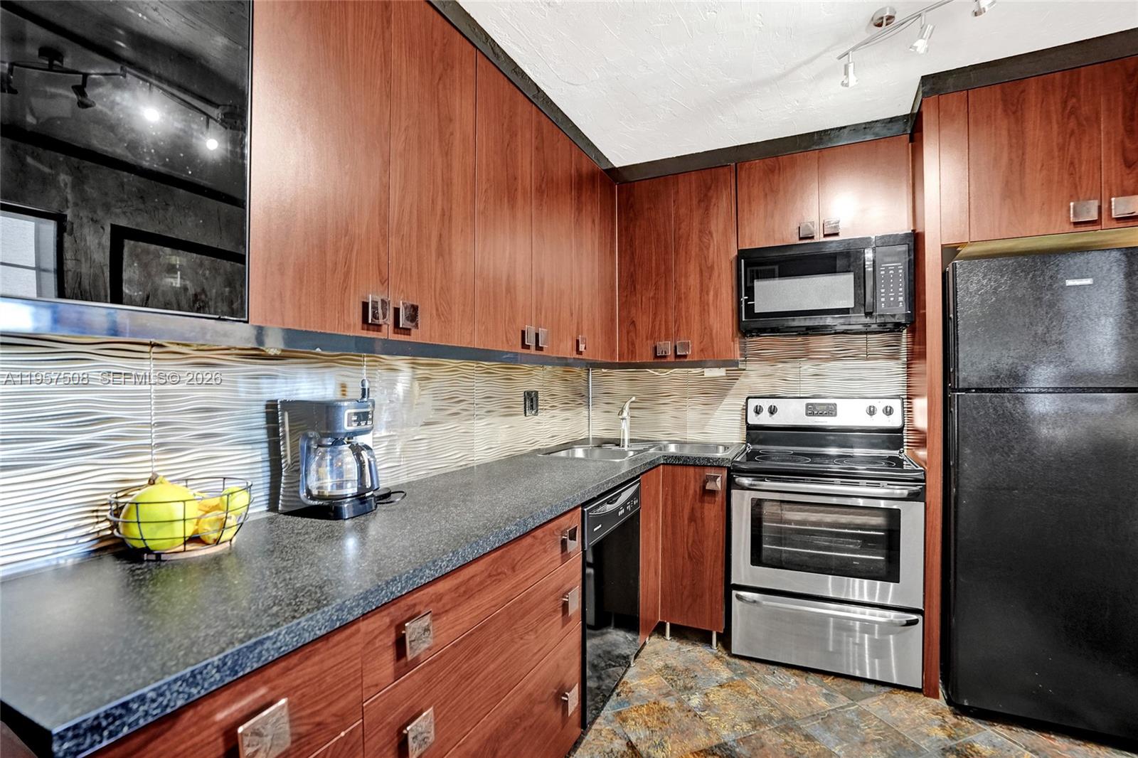 A kitchen features wood cabinets, dark countertops, stainless steel appliances, and a textured backsplash — 1000 NE 12th Ave # 505, Hallandale Beach FL 33009, HALLANDALE BEACH, FL