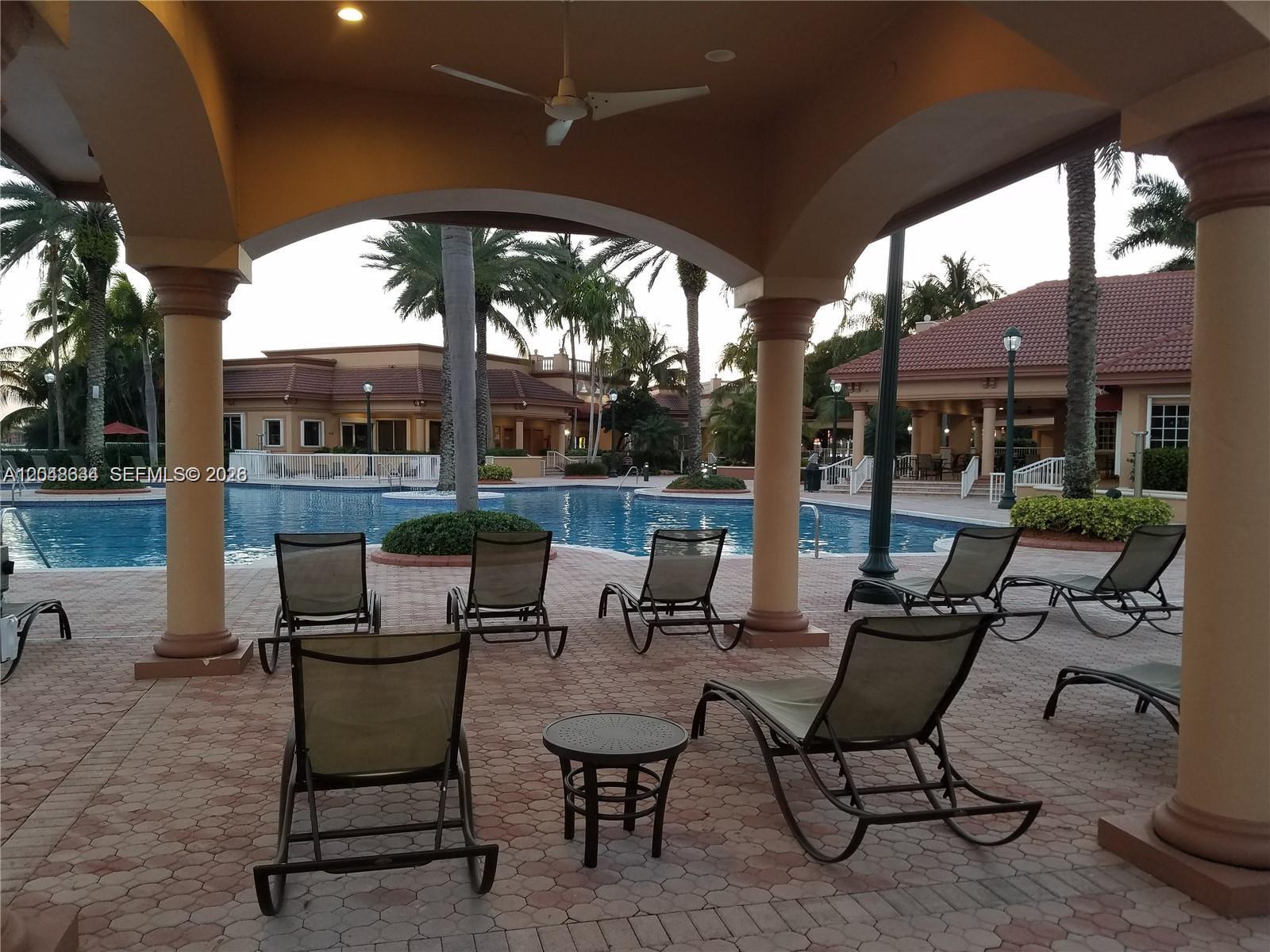 A covered patio with lounge chairs overlooks a swimming pool and surrounding buildings — 18741 SW 25th Ct # 18741, Miramar FL 33029, MIRAMAR, FL